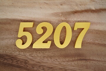 Golden Arabic numerals on a real brown and white wooden floor number 5207