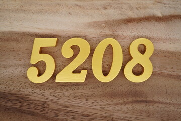 Golden Arabic numerals on a real brown and white wooden floor number 5208