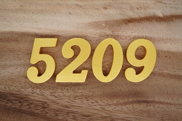 Golden Arabic numerals on a real brown and white wooden floor number 5209