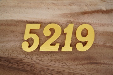 Golden Arabic numerals on a real brown and white wooden floor number 5219