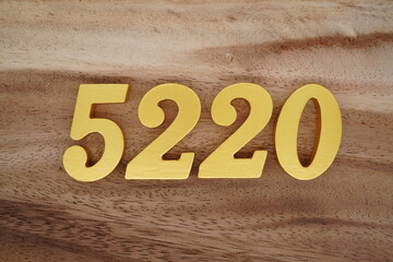 Golden Arabic numerals on a real brown and white wooden floor number 5220