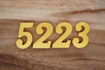 Golden Arabic numerals on a real brown and white wooden floor number 5223