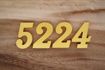 Golden Arabic numerals on a real brown and white wooden floor number 5224