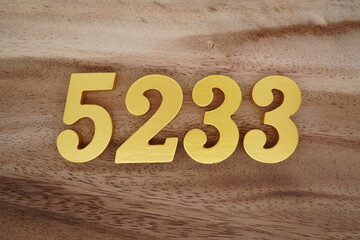 Golden Arabic numerals on a real brown and white wooden floor number 5233