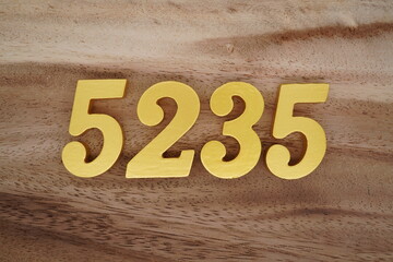 Golden Arabic numerals on a real brown and white wooden floor number 5235