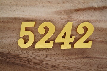 Golden Arabic numerals on a real brown and white wooden floor number 5242