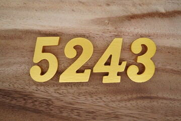 Golden Arabic numerals on a real brown and white wooden floor number 5243