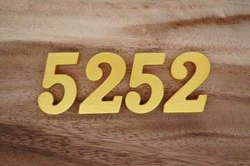 Golden Arabic numerals on a real brown and white wooden floor number 5252