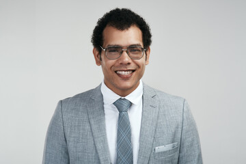 Im the owner of a successful business. Studio shot of a businessman wearing glasses while standing against a grey background.