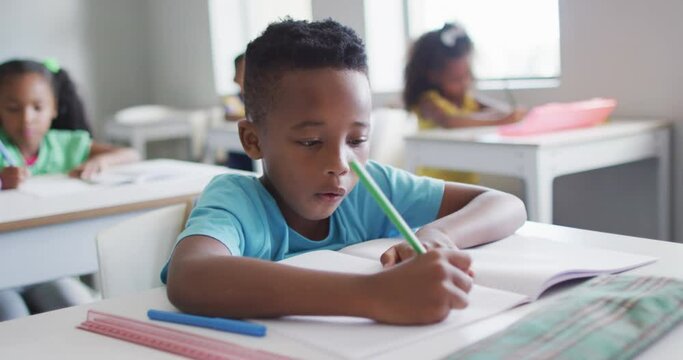 Video of focused african american boy doing lessons in classroom