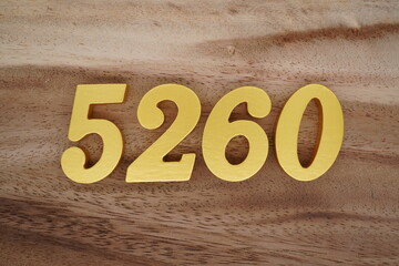 Golden Arabic numerals on a real brown and white wooden floor number 5260