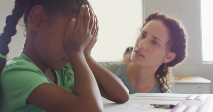 Video of caucasian female teacher supporting sad african american girl during lessons