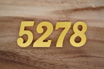 Golden Arabic numerals on a real brown and white wooden floor number 5278