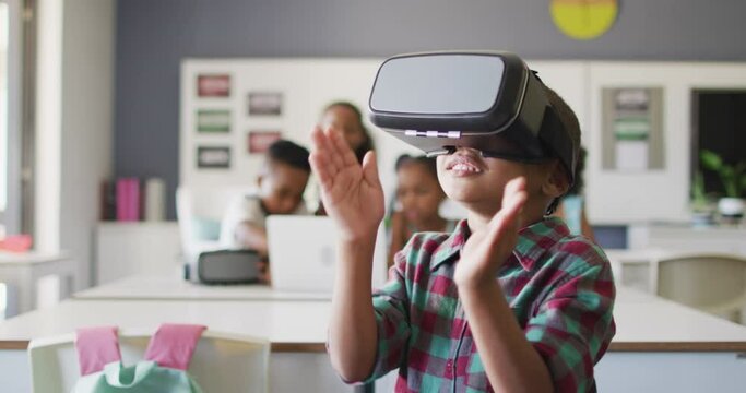 Video of happy african american boy wearing vr headset in classroom