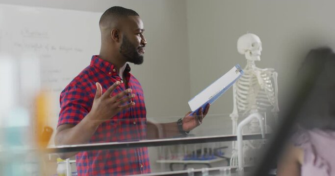 Video of happy african american teacher with class of diverse pupils during anatomy lesson