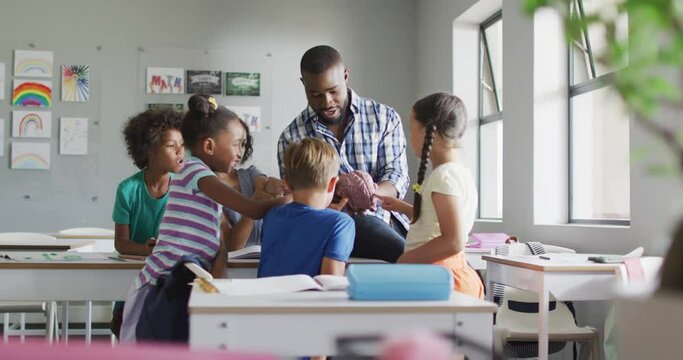 Video of happy african american male teacher and class of diverse pupils during biology lesson