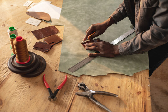 Midsection of african american young craftsman making outline on leather while working in workshop