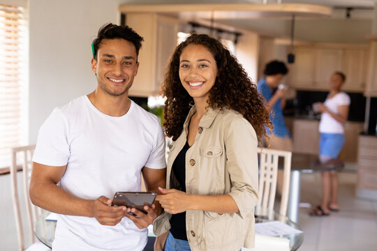 Portrait of smiling young biracial businessman and businesswoman with digital tablet at home office