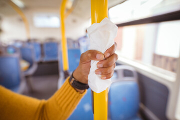Cropped hand of african american mid adult businesswoman holding handle with napkin in bus