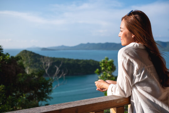 Portrait image of a young asian woman looking at a beautiful sea view from resort terrace