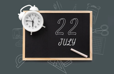 july 22. 22th day of month, calendar date. Blackboard with piece of chalk and white alarm clock on green background. Concept of day of year, time planner, summer month