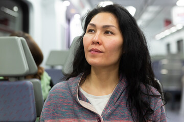 Smiling young adult woman in casual wear traveling by intercity train