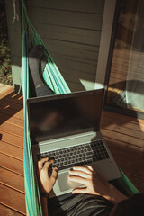 A top view of man working in hammock near cottage. Distant work, freelancer