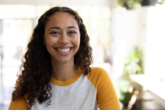 Portrait of smiling beautiful african american young woman with curly hair at cafe
