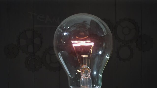 Animation of bulb lightening over brown background with gears