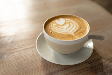 High angle close-up of fresh cappuccino with froth art served in mug on table at cafe