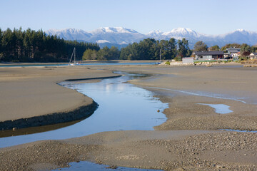 estuary at low tide with snowy mountains