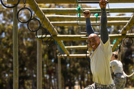 African american male soldier climbing monkey bars during obstacle course at boot camp - Powered by Adobe