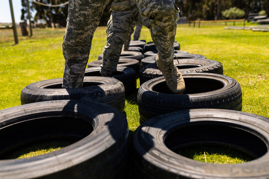 Low section of group of diverse soldiers walking on tires during obstacle course at boot camp