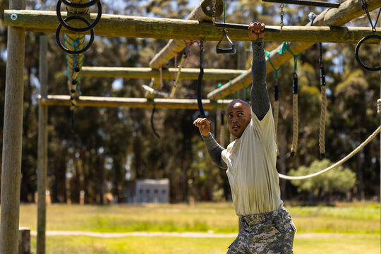African american male soldier climbing monkey bars during obstacle course at boot camp