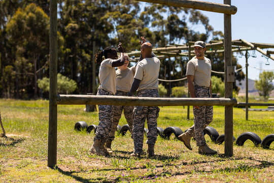 Group of male and female diverse soldiers high fiving each other at boot camp