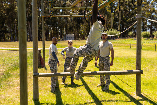 African american soldier climbing monkey bars during obstacle course at boot camp