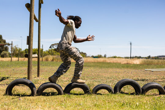African american male soldier walking on tires during obstacle course at boot camp
