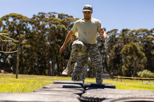 Caucasian male soldier walking on tires during obstacle course at boot camp