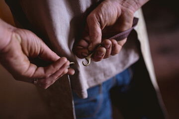 Midsection of blacksmith fastening hook of apron while working in industry