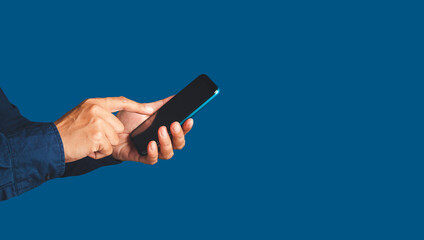Close-up of hands using a mobile phone while standing over a blue background