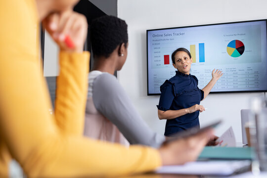 Businesswoman explaining strategy to female colleagues over chart in board room - Powered by Adobe