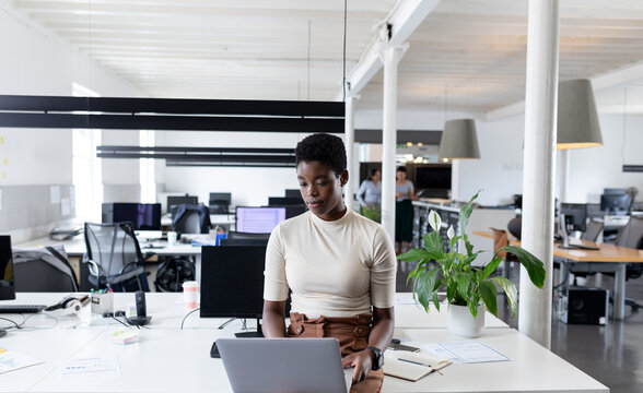 African-american businesswoman working on laptop in creative office
