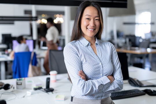 Portrait of confident asian businesswoman with arms crossed in creative office