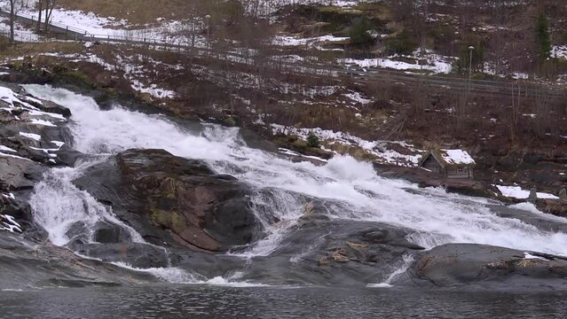 Slow motion waterfall past mill house. Looping, wide shot