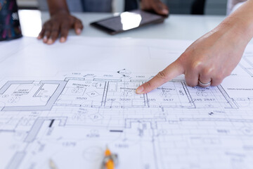 Cropped image of female architects discussing over blueprint during meeting in office