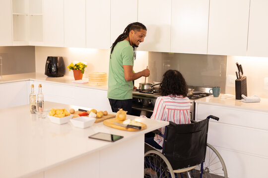 African american disabled woman on wheelchair and husband cooking in the kitchen