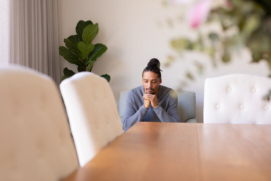 Thoughtful african american young man sitting on a chair at home