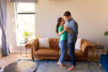 Caucasian couple dancing together in the living room at home