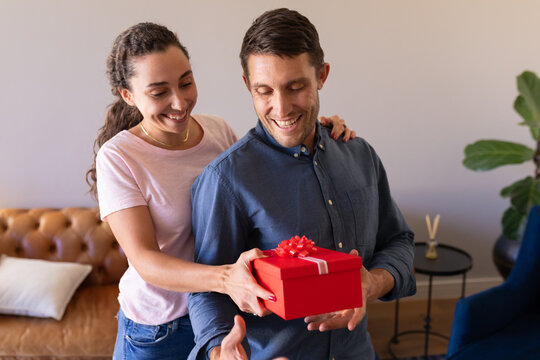 Caucasian woman surprising her husband with a gift at home