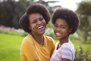 Portrait of happy mother and daughter with afro hairstyle embracing in backyard